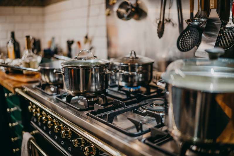 Hands holding a modern stainless steel pressure cooker on a rustic kitchen counter